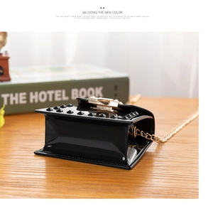Detail of black glossy jelly bag with golden pyramid studs and metal chain strap