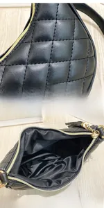 Detail of black quilted faux leather handbag with golden zipper and spacious interior