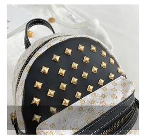 Close-up of golden pyramid studs and textured floral synthetic leather on a mini backpack