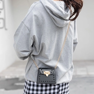 Fashionable black rivet jelly bag with gold chain strap shown on model's shoulder
