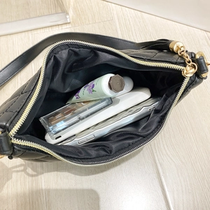 Sac hobo noir matelassé avec bandoulière montrant l'espace de rangement intérieur