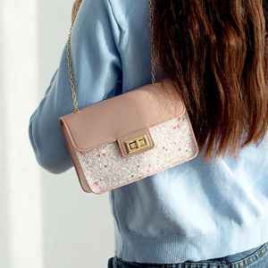 Pink sequin shoulder bag with gold chain strap and metallic lock shown on model
