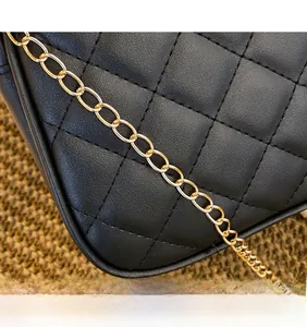 Detail of black quilted leather texture and premium gold metal chain strap on handbag