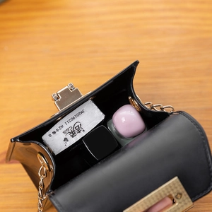 Fashionable black mini jelly bag with gold chain showing internal storage capacity