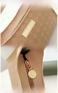 Detail of checkered shoulder bag with golden brand plate and premium metal zipper closure