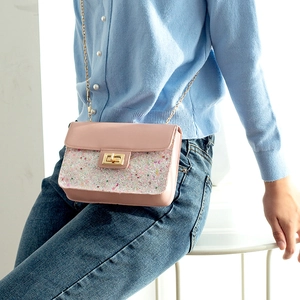 Pink crossbody bag with glitter sequins and gold chain strap shown on model shoulder