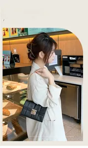 Sac bandoulière noir matelassé avec chaîne dorée présenté dans un décor de café