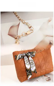 Détail du sac matelassé marron avec chaîne dorée et nœud en ruban au motif nautique