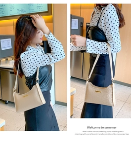 Detailed view of beige plaid underarm bag featuring a signature gold metal nameplate