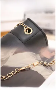 Détail d'un sac à main en cuir grainé noir avec chaîne dorée et accessoires métalliques