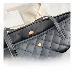 Detail shot of the secure gold magnetic closure on a black quilted tote bag