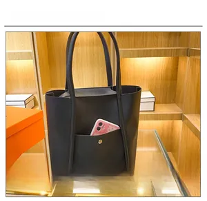 Close-up of black leather tote bag featuring a practical front pocket for smartphone storage