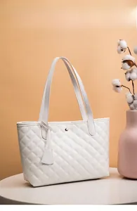 Dettaglio della borsa tote trapuntata bianca con bottone magnetico dorato e spalline