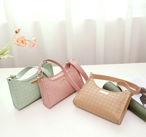 Detailed view of woven texture underarm bags in mint, pink, and khaki with gold metal accents