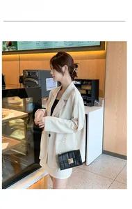 Détail du sac bandoulière noir matelassé avec chaîne dorée et blazer beige chic