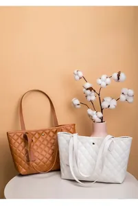 Dettaglio di borse shopper trapuntate marroni e bianche con eleganti rivetti in metallo
