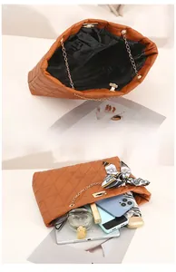 Détail de l'intérieur spacieux du sac matelassé marron avec foulard et chaîne dorée