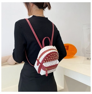 Close-up of mini monogram backpack with red leather trim and gold rivet details