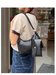 Detail of black crocodile texture underarm bag set with golden metal hardware