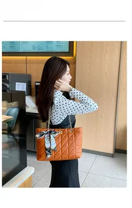 Détail du sac cabas matelassé orange avec chaîne dorée et foulard en soie décoratif