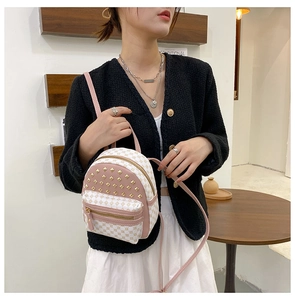 Detail of pink and white contrast mini backpack featuring gold studs and geometric patterns