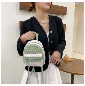 Detailed view of mint green mini backpack with checkered pattern and gold studs on front