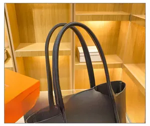 Macro detail of the rounded leather shoulder strap on a large black tote bag