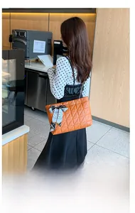 Détail d'un sac à bandoulière matelassé orange avec un foulard en soie fleurie
