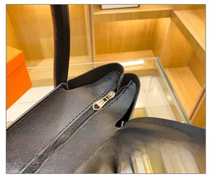 Close-up of golden metal zipper and black lychee grain leather on tote handbag