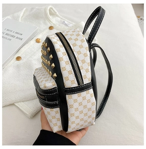 Detail of mini black and white backpack featuring gold studs and clover flower pattern