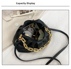 Internal capacity of black cloud pouch showing phone and cosmetics with gold chain