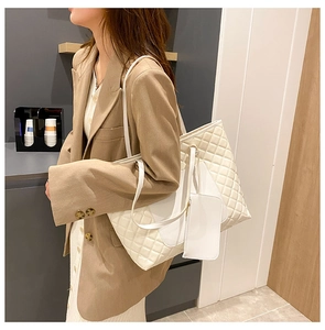 Detailed view of white quilted tote bag set including matching zip pouch and double straps