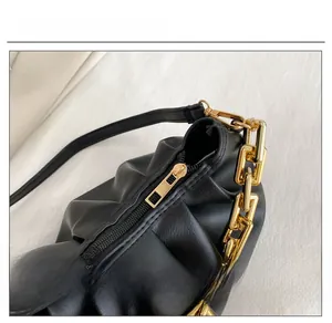 Macro detail of high-quality smooth zipper and golden chain on black ruched cloud bag