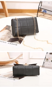 Détail d'un sac bandoulière noir matelassé avec chaîne dorée et texture en similicuir chic
