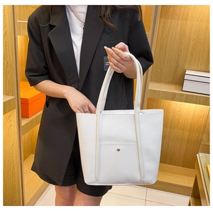 Detail of white PU leather tote bag with slim long handles and gold rivet on pocket
