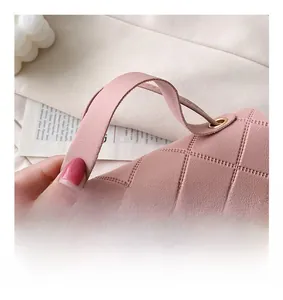 Detail shot of a pink quilted faux leather handbag with a gold-tone twist lock closure