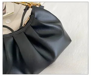 Detail of black pleated cloud bag with chunky gold chain strap and PU leather texture