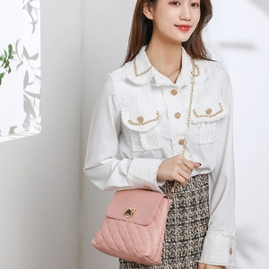 Pink quilted bucket bag with heart lock and chain strap worn by a model in soft light
