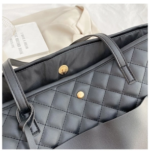 Close-up of black quilted tote bag with gold magnetic buckle and fine stitching detail