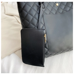 Detailed close-up of quilted black tote bag set with golden hardware and small pouch