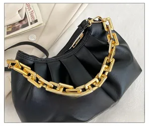 Detailed view of black pleated cloud bag with chunky gold chain on a beige blazer