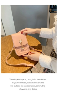 Detailed view of pink phone bag featuring a cat metal buckle and pearl charm accessory