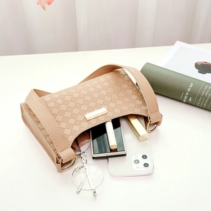 Minimalist beige quilted shoulder bag with gold clasp and daily essentials on table