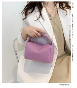 Chic purple lychee texture pillow bag with gold chain strap shown in a lifestyle setting