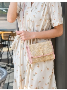 Detail of woven straw crossbody bag with golden tassel and pink faux leather strap