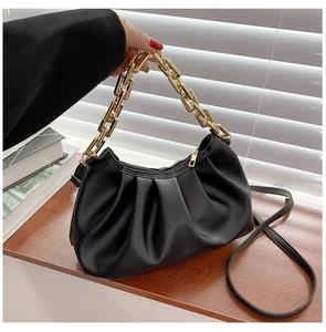Detail of black pleated cloud bag with chunky gold chain handle and zipper closure