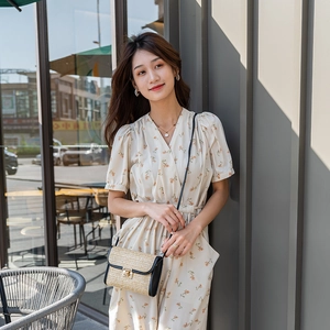 Chic beige straw and black leather crossbody bag with gold buckle shown on a model