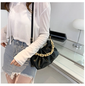 Detail of black pleated cloud bag featuring chunky gold chain and adjustable strap