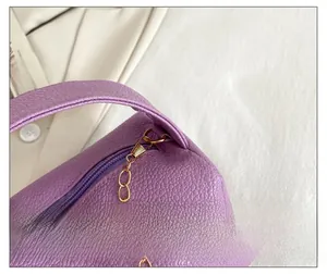 Detail of premium golden zipper and metallic chain strap on purple lychee leather bag
