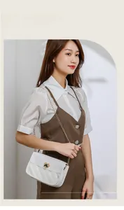 Close-up of white quilted crossbody bag with heart-shaped metal clasp and gold chain strap